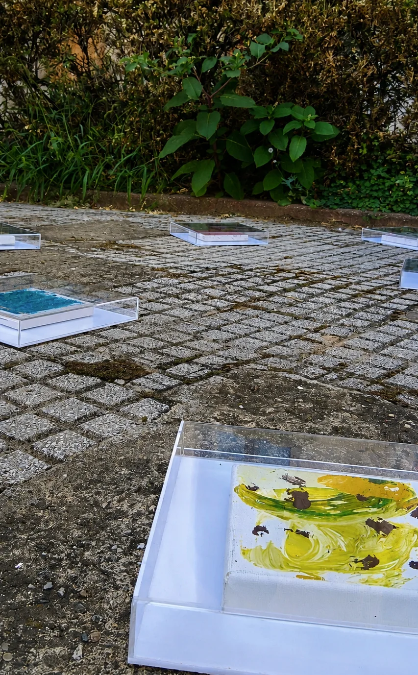 Detaliu al instalației SEEDS de Adrian Dică, cu picturi protejate în casete transparente și așezate pe pavajul curții Palatului Cantacuzino, București, 2026